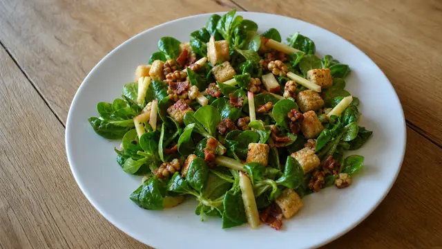 Feldsalat mit Speck und Croûtons auf einem Teller