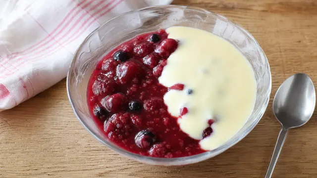 Rote Grütze mit Vanillesauce auf einem Teller