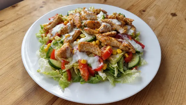 Bunter Salat mit Hähnchenstreifen auf einem Teller